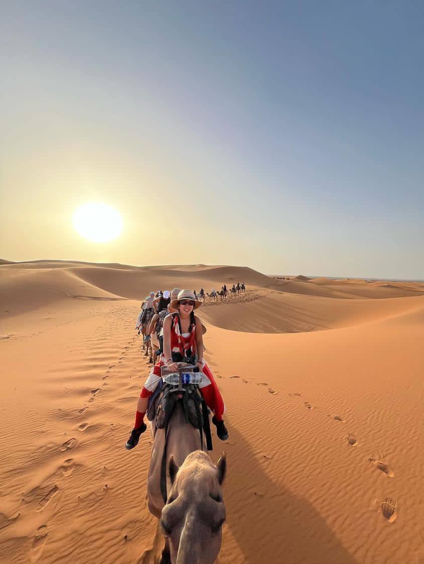 A rider on a camel and a caravan on the dunes